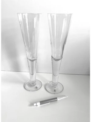 Två höga ölglas / champagneglas från Hovmantorp glasbruk - Ett par stilrena höga glas från Hovmantorp, i populära serien ”Prosit”, formgivna av erkände och prisbelönte svenske glasdesignern Rune Strand (1924-2000), lanserade under 1970-talet. Serien har blivit vida erkända för sin munblåsta smala, avsmalnande form med sin stilrena design. De har Hovmantorp-märkning på foten. 29 cm höga och 8 cm i diameter, så stora glas. Brukar användas som gedigna champagneglas pga formen, men är från början designade som pilsnerglas. Oavsett, så är de ett stycke svens