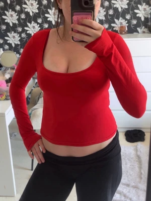 Röd långärmad topp med djup urringning - Snygg röd långärmad topp med djup, rund urringning. Modellen är tight och croppad, vilket ger en trendig look. Tillverkad i mjukt bomullsmaterial som känns skönt mot huden. Perfekt att styla med både jeans och kjol. Använd 1 gång, den är från shein!