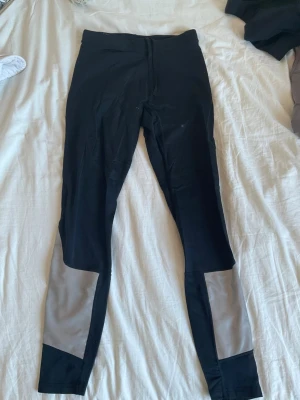Svarta fodrade/varma leggings med gråa detaljer - Helt fantastiska och varma tights som är perfekt för vinterträningen! De håller garanterad allt varmt och de är sköna. De har hög midja och är tillverkade i ett stretchigt material som sitter tajt mot kroppen. Perfekta för träning eller en sportig look.