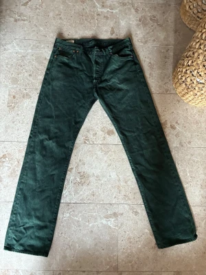 Mörkgröna raka jeans- Levis 501 - Säljer ett par mörkgröna jeans med rak passform. Jeansen har normal midja och är tillverkade i ett robust denimtyg. Perfekta för dig som vill ha en unik färg på dina jeans och gillar en avslappnad stil. W34 L32