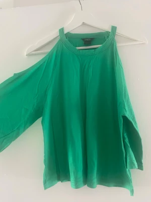 Grön offshoulder topp - Snygg grön topp med offshoulder-design och vida ärmar. Toppen har en lös passform och tunna axelband. Perfekt för dig som vill ha en trendig och luftig look.