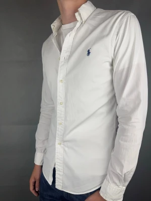 Ralph Lauren skjorta - Ralph Lauren Skjorta Märke: Polo Ralph Lauren Storlek: SPassform: Customfit Färg: Vit Skick: Mycket bra, möjligtvis superlite gulnad under armarna (syns knappt) Beskrivning: tunnare skjort material. Modellen på bilden: 183 cm / 74 kg