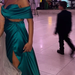 Grön klänning från kosovo - Säljer en elegant turkos långklänning med offshoulder och omlott-detalj i midjan. Klänningen har en hög slits framtill och är tillverkad i ett glansigt satin material som ger en lyxig känsla. Perfekt för speciella tillfällen. Den är köpt från Kosovo. pris kan diskuteras. Använt endast en kväll!
