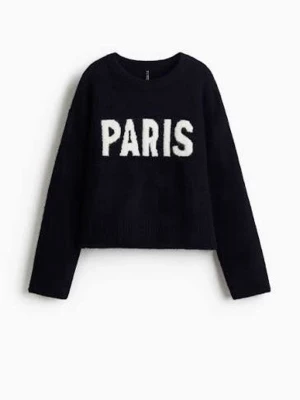Svart stickad tröja med PARIS-tryck - Cool svart stickad tröja med vit text 'PARIS' framtill. Tröjan har rund halsringning och långa ärmar. Perfekt för dig som gillar streetstyle och vill ha en trendig look. Mjuk och skön att bära under kyliga dagar.
