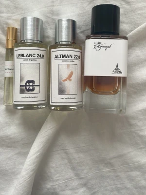 Fyra exklusiva parfymer mixade märken - Fyra parfymer: två från One Bold Chemist (LEBLANC 24.0 och ALTMAN 22.0) i genomskinliga flaskor med silverlock, en bruntonad parfym från Paris corner med svart lock och vit etikett, samt en liten provflaska med guldfärgat lock. Modern design och stilrena etiketter.