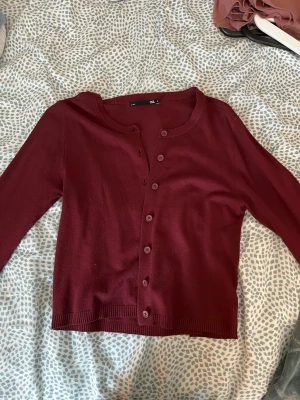 Vinröd kofta - Vinröd kofta från 157 med rund halsringning och knäppning framtill. Långärmad modell med ribbade muddar vid ärmslut och nederkant. Väldigt bra skick och inte så använd.