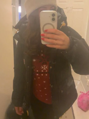 Svart dunjacka från Fjällräven - Säljer en svart dunjacka från Fjällräven med guldfärgade detaljer på snörningarna och klassisk logga på bröstet. Jackan har hög krage, stora framfickor med knappar och en puffig, varm design perfekt för kalla vinterdagar.