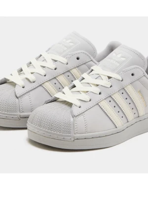 Adidas Superstar vita sneakers - Klassiska Adidas Superstar sneakers i vitt läder med de ikoniska tre ränderna i offwhite på sidorna. Skorna har vit gummitå, vita skosnören och Adidas-logga på plösen. Perfekta för en clean och stilren look.