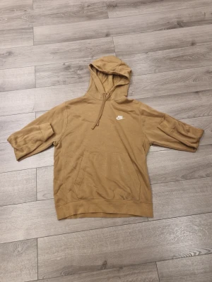 Beige hoodie från Nike - Säljer en beige hoodie från Nike med klassisk logga på bröstet. Hoodien har huva med dragsko och en stor magficka. Tillverkad i mjukt material med borstad insida för extra komfort. Perfekt för en avslappnad och sportig stil.