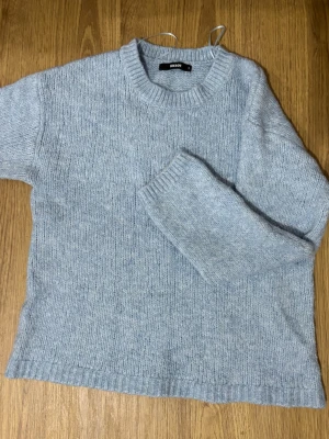Ljusblå stickad tröja från Bik Bok - Mysig ljusblå stickad tröja från Bik Bok med grovstickad struktur och ribbad halsringning. Perfekt för kyliga dagar och enkel att matcha med jeans eller kjol. Tröjan har en klassisk passform och mjukt material.