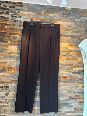 Kostymbyxor från Twist & Tango - Hej!🌸 Jag säljer mina snygga kostymbyxor från Twist & Tango med vida ben och pressveck. Byxorna har hällor för bälte, två sidofickor fram och två passpoalfickor bak. Perfekta för en clean och stilren look. Materialet känns mjukt och har en lätt glans. Sparsamt använda. Nypris 1999kr! 