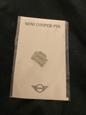 MINI Cooper pin i silver - Snygg pin i form av en MINI Cooper, tillverkad i rostfritt stål med silverfärg. Perfekt att fästa på jackan, väskan eller kepsen för att visa din kärlek till MINI. Kommer på originalkort med MINI-logga.