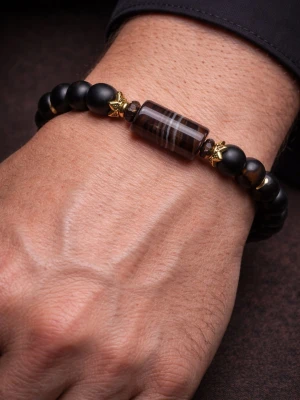 Svart pärlarmband med guldstjärnor - Oanvänt. Snyggt armband med mattsvarta pärlor och en  mittsten inringad av guldfärgade detaljer ger en elegant och lyxig touch. Passar lika bra till vardag som till fest.  Detaljer: • Elastiskt band  • Mattsvarta pärlor 8 mm • Dekorativ unik mittsten • Guldfärgade detaljer  Perfekt som present eller för dig som vill komplettera din stil med en stilren accessoar.  Passande handled som är 17 cm +- 0,5 cm