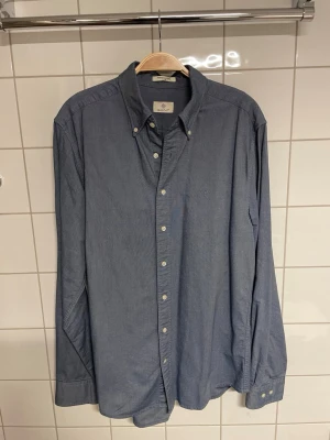 Blå Oxford gant skjorta  - Klassisk blå Oxford skjorta från Gant med button-down krage och vita knappar. Skjortan har lång ärm och är tillverkad i mjuk bomull. Perfekt till jeans eller chinos för en clean och stilren look.