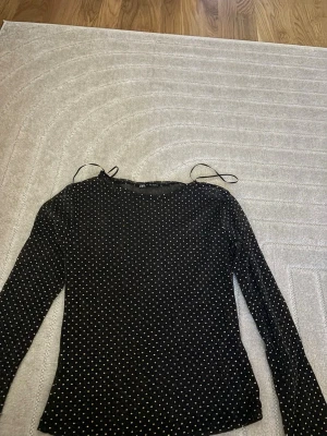 Svart mesh topp med prickar från Zara - Snygg svart mesh topp från Zara med små vita prickar över hela. Toppen har lång ärm och är lätt transparent vilket ger en cool vibe. Perfekt att styla med jeans eller kjol för en trendig look.