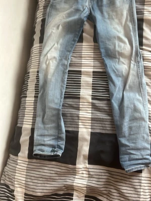 Ljusblå slim fit jeans från Replay(förhandlar nytt pris) - Snygga ljusblå slim fit jeans från Replay med klassisk femficksdesign och diskreta slitningar. Jeansen har en modern passform och är perfekta för en avslappnad stil. Materialet är mjukt och stretchigt för extra komfort.