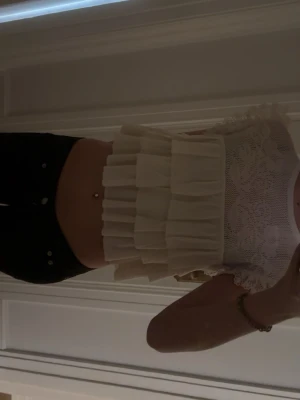 Vit volangblus med spetsdetaljer - Supersöt vit blus med volanger och spets upptill. Croppad modell med ärmlös design och romantiska detaljer. Perfekt för dig som gillar en feminin och trendig stil.