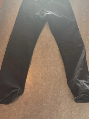 Svarta Levi's jeans straight fit - Säljer ett par svarta jeans från Levi's med klassisk straight fit. Jeansen har fem fickor, normal midja och är tillverkade i denim. Perfekta för dig som gillar en tidlös och enkel stil.