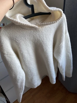 Vit fluffig hoodie med huva - Mysig vit stickad hoodie i mjukt material med huva och ribbade muddar vid ärmslut och nederkant. Den är inte jätteanvänd men har lite lite knottrar på sig. Fortfarande supermjuk och är i XS från bikbok, passar även som S