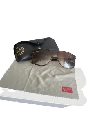 Bruna Ray-Ban solglasögon - Snygga solglasögon från Ray-Ban med bruna bågar och tonade glas. Modellen har en klassisk, rektangulär form och kommer med originalfodral och putsduk. Perfekta för att lyfta din stil under soliga dagar.