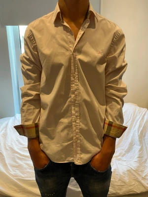 Burberry piké - Väldigt stilren rosa  Burberry skjorta i ny skick. Storlek M. Killen på bilden är 182 och väger 73kg. Perfekt inför sommaren. 
