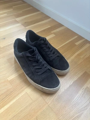 Svarta vagabonds i mocka - Svarta sneakers i mocka med klassisk låg profil och vita sulor. Skorna har svarta skosnören och en stilren design som passar till det mesta. Perfekta för dig som gillar en clean och enkel look.
