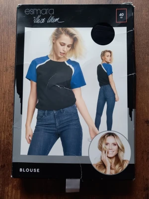 Svart och blå blus från Esmara storlek 40 - Trendig blus i svart och blått med vita detaljer från Esmara by Heidi Klum. Blusen har korta ärmar och är tillverkad i mjuk, 100% viskos. Dragkedja i ryggen för enkel påklädning. Perfekt för en sportig och avslappnad stil. Storlek 40