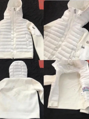 Vit dunjacka med huva från Moncler - Snygg vit dunjacka från Moncler med quiltad framsida och huva. Jackan har dragkedja, två fickor fram och Moncler-logga på ärmen. Ärmar och rygg är i mjukt tyg för extra komfort. Perfekt för kalla vinterdagar.