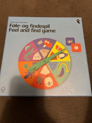 Feel and Find Game sällskapsspel - Feel and Find Game är ett färgglatt sällskapsspel där man snurrar en pil och letar efter matchande brickor med olika djur och texturer. Spelet kommer i en blå kartong och innehåller flera färgglada brickor och en snurra. Passar för barn från 3 år.