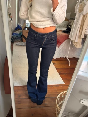 Mörkblå bootcut jeans - Snygga mörkblå bootcut jeans med klassiska fickor fram och bak samt kontrastsömmar. Jeansen har låg midja och är tillverkade i ett stretchigt denim-material som sitter tight upptill och släpper ut vid benen. Perfekta för dig som gillar en retrostil. Dragkedjan är sne som gör jeansen lite coolare och unika !❤️❤️ Jag är 174cm ⭐️ W26 L32