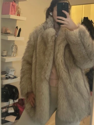 Beige fuskpälsjacka från Zara - Snygg och fluffig beige fuskpälsjacka från Zara. Jackan har en rak och oversized passform med mjukt foder och bred krage. Perfekt för att hålla värmen och ge en trendig look under kalla dagar.