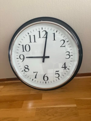 Stor rund väggklocka i svart och vit - Snygg och enkel väggklocka med svart ram och vit urtavla. Klassisk design med tydliga svarta siffror och visare. Perfekt för att hålla koll på tiden och passar in i de flesta rum.