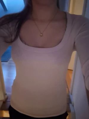 Ljusbeige ribbad långärmad topp - Snygg ljusrosa ribbad topp med lång ärm och bred, rundad urringning. Figurnära passform som framhäver siluetten. Perfekt att styla med jeans eller kjol. OBS. Är lite missfärgad så den kan se lite beige ut i vissa ljusrosa men är fof ljusrosa.