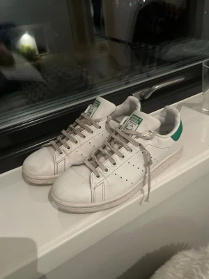 Adidas Stan Smith vita sneakers - Klassiska vita Adidas Stan Smith sneakers med gröna detaljer på hälen.för dig som vill ha skorna som är inne och och trendiga vi kan byta och snabb affär kan du få dom för 200