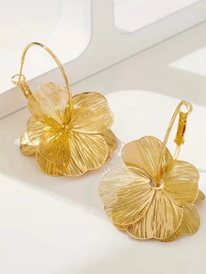 Stora guldfärgade blomörhängen - Säljer ett par stora, guldfärgade örhängen i form av blommor. Örhängena har en öppen, luftig design med tunna metalltrådar som bildar blomblad och sitter på klassiska hoops. Perfekta för dig som vill sticka ut med en unik accessoar.