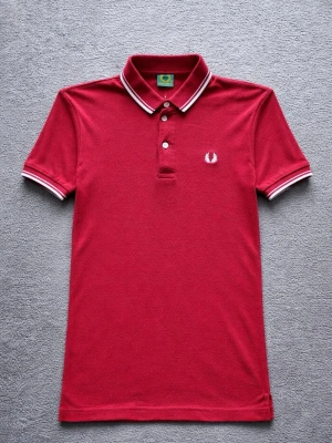 Fred Perry Polo Shirt – Classic British Mod Style – M - Klassisk Fred Perry polo shirt i röd färg med den ikoniska laurel wreath-loggan på bröstet.  En tidlös piké som passar perfekt för British mod / terrace style eller en clean casual outfit.  Detaljer: • Fred Perry • Storlek M • Mycket bra skick • Klassisk polokrage med kontrastdetaljer • Broderad logotyp på bröstet • Röd färg  Perfekt till jeans, chinos eller shorts för en klassisk British casual look.  📦 Skickas snabbt 💬 Hör gärna av dig vid frågor