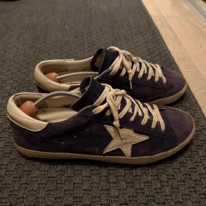 Golden goose - Snygga mörkblå mocka sneakers från Golden Goose med vit stjärna på sidan och matchande vit snörning. Mockan är i fint skick men underdelen av sulan är  ganska sliten. Storlek 43. Nypris ca 6000kr dustbag box och kvitto finns. Fråga gärna för fler bilder!