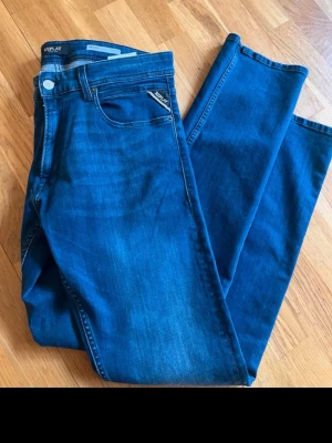 Blå slim fit jeans från Replay - Snygga blå slim fit jeans från Replay med klassisk femficksmodell och diskret Replay-logga på myntfickan. Jeansen har en djup indigo färg och är tillverkade i stretchigt denimtyg för skön passform.