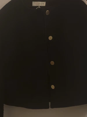 Svart Zara jacka med guldfärgade knappar - Stilren svart jacka från ZARA i storlek M , passar även S , liten i storlek med rund halsringning och fyra guldfärgade knappar framtill. Kortare modell som passar perfekt till både jeans och kjol. Enkel och klassisk design som är lätt att matcha. Jackan säljs för 250 kr endast använd 2-3 gånger