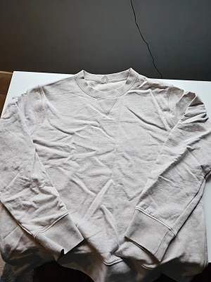 Beige sweatshirt med rund hals - En basic beige sweatshirt från arket med rund halsringning och ribbade muddar vid ärmar och nederkant. Tröjan har en klassisk relaxed fit och är tillverkad i mjukt bomullsmaterial. Perfekt för en chill och enkel stil. Tvättas innan den skickas! Skriv ifall ni har funderingar🙌👍