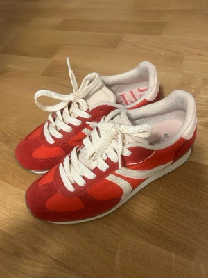 Röda  sneakers från stradivarius  - Snygga sneakers i rött och vitt med klassisk retrostil. Skorna har vita snören, paneler i mocka och textil samt en vit sula. Perfekta för dig som gillar färg och vill sticka ut lite extra i vardagen.