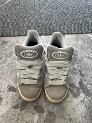 Grå Adidas sneakers campus - Snygga grå sneakers från Adidas i mocka med vita detaljer och klassiska tre ränder på sidan. 