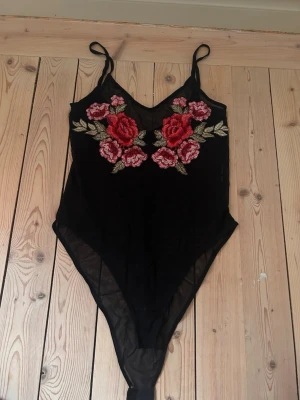 Svart body med Rosdetaljer - Jag säljer nu denna super snygga bodyn. Den är i ett lite genomskinligt material. Super skön och passar perfekt till en kjol eller jeans. 💕