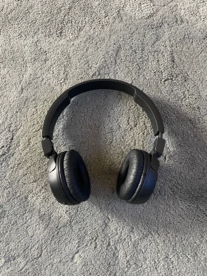Svarta on-ear hörlurar - Snygga svarta on-ear hörlurar med vadderade kåpor och justerbart huvudband. Perfekta för musik, gaming eller videos. Slitstark design i plast och konstläder för bekväm användning under längre tid.