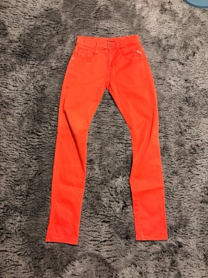 Röda slim fit jeans - W29/L32 107/36 Snygga röda slim fit jeans med klassisk femficksdesign och raka ben. Jeansen har knappgylf och är tillverkade i ett mjukt bomullsmaterial med lite stretch för extra komfort. Perfekta för dig som vill sticka ut med färg.