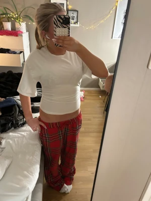Vit tajt t shirt från Gina tricot - Mysiga pyjamasbyxor i rött med klassiskt rutigt mönster. Byxorna har en avslappnad passform och resår i midjan för extra komfort. Perfekta för chillkvällar hemma eller när du vill ha det extra bekvämt.