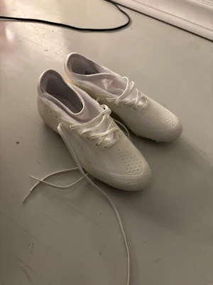 Vita adidas crazyfast storlek 40 2/3 - Säljer ett par stilrena vita fotbollsskor med klassisk snörning och dobbar för bra grepp på planen. Knappt använda pågrund av fel storlek