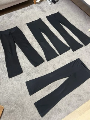 Svarta bootcut leggings - Fyra par svarta leggings med bootcut-modell. Alla har hög midja och stretchigt material, perfekta för en avslappnad och trendig look. Ett par har dragsko i midjan för extra komfort. Passar till många olika stilar och är riktigt sköna.