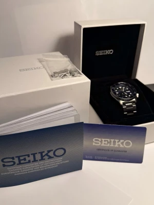 Seiko 5 sports automatisk klocka blå/silver - Full set - Säljer min helt nya seiko 5 sports som är automatisk. Snygg automatisk klocka från Seiko med blå urtavla och matchande blå vridring. Klockan har tydliga indexmarkeringar, dag- och datumvisning samt robust länkarmband i silverfärgat stål. 