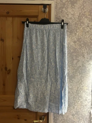 Ljusblå blommig midikjol - Ljusblå blommig midikjol kjol från lager 157. Med fickor och slit på båda sidorna. Mycket bra skick använd fåtal gånger. Hör av vid frågor!💗